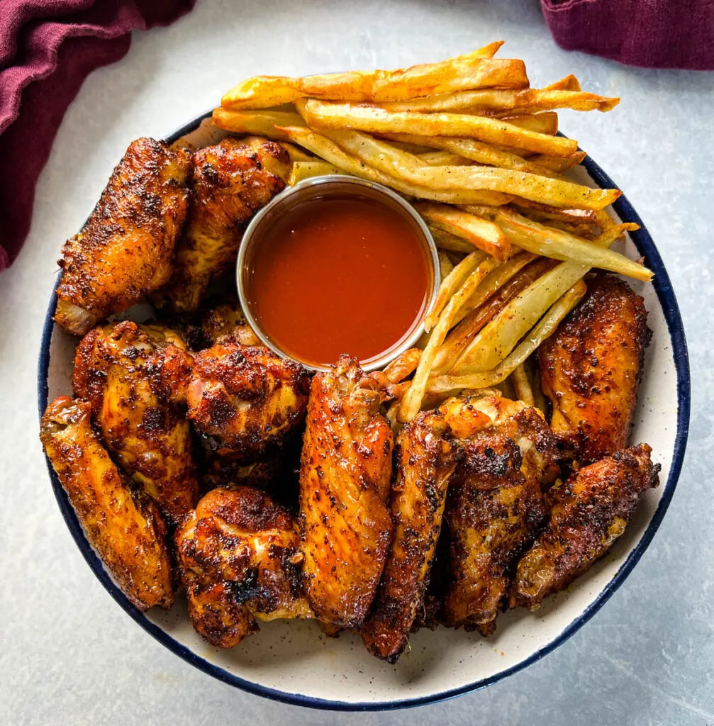 Cajun chicken wings in a bowl with french fries