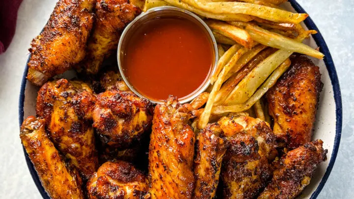 Cajun chicken wings in a bowl with french fries