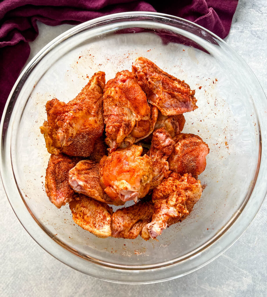 raw chicken wings seasoned in Cajun rub in a glass bowl