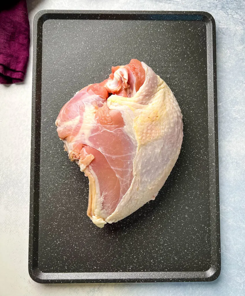 raw bone-in turkey breast on a sheet pan