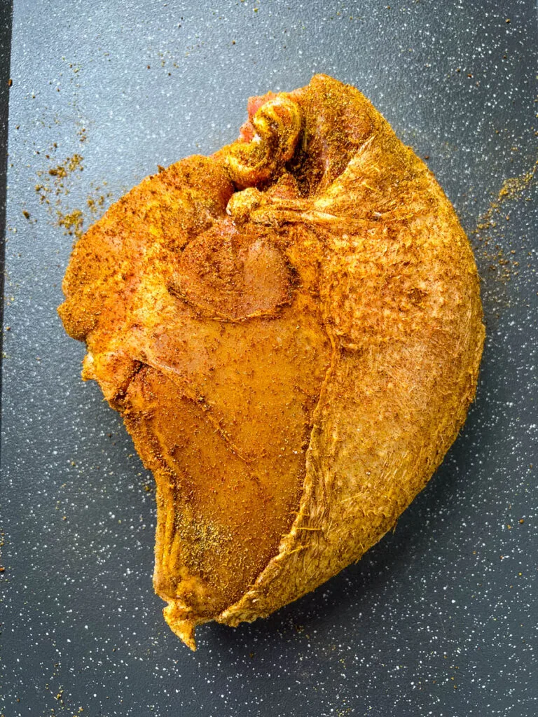raw seasoned bone-in turkey breast on a sheet pan