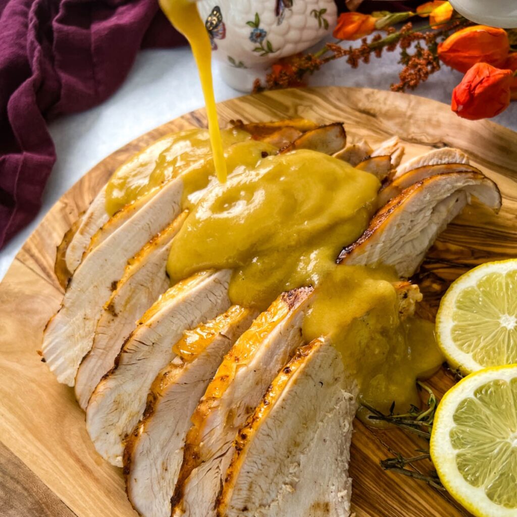 gravy drizzled over slices of Crockpot slow cooker turkey breast on a cutting board