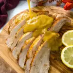 gravy drizzled over slices of Crockpot slow cooker turkey breast on a cutting board