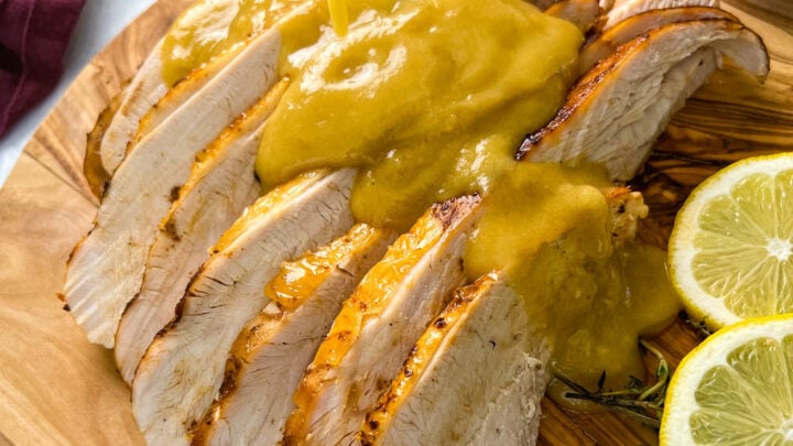 gravy drizzled over slices of Crockpot slow cooker turkey breast on a cutting board