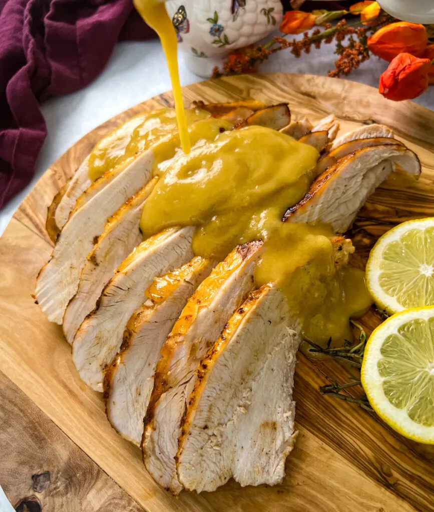 gravy drizzled over slices of Crockpot slow cooker turkey breast on a cutting board