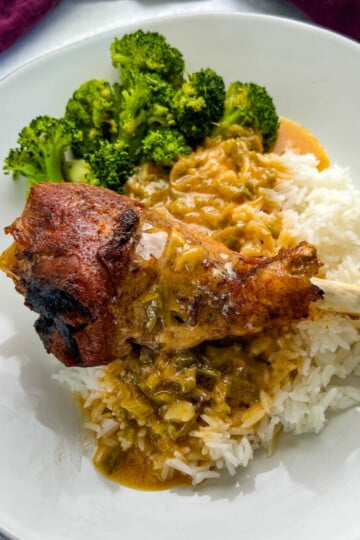 baked turkey leg on a plate with rice, gravy, and broccoli