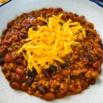 ground chicken chili with cheese in a white bowl