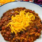 ground chicken chili with cheese in a white bowl
