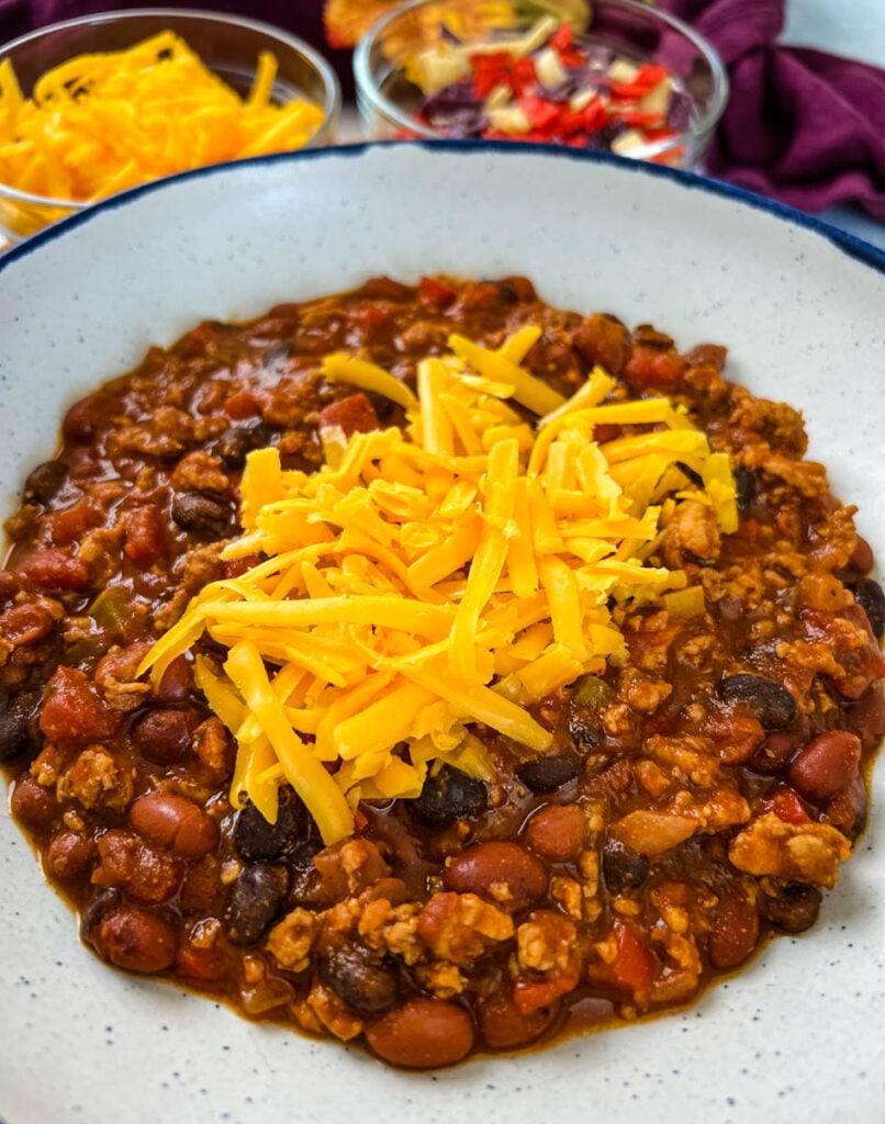 ground chicken chili with cheese in a white bowl