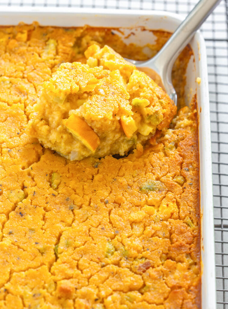 a spoonful squash dressing in a baking dish