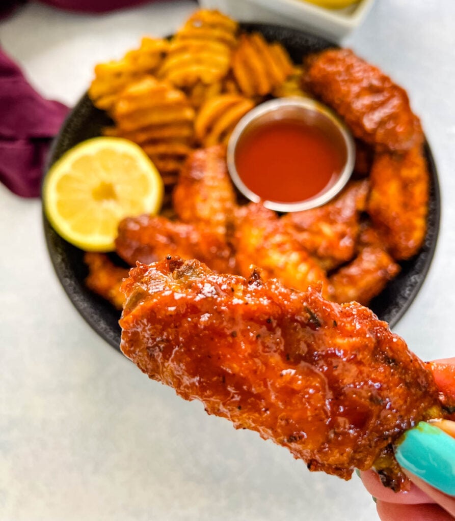 person holding hot lemon pepper chicken wing