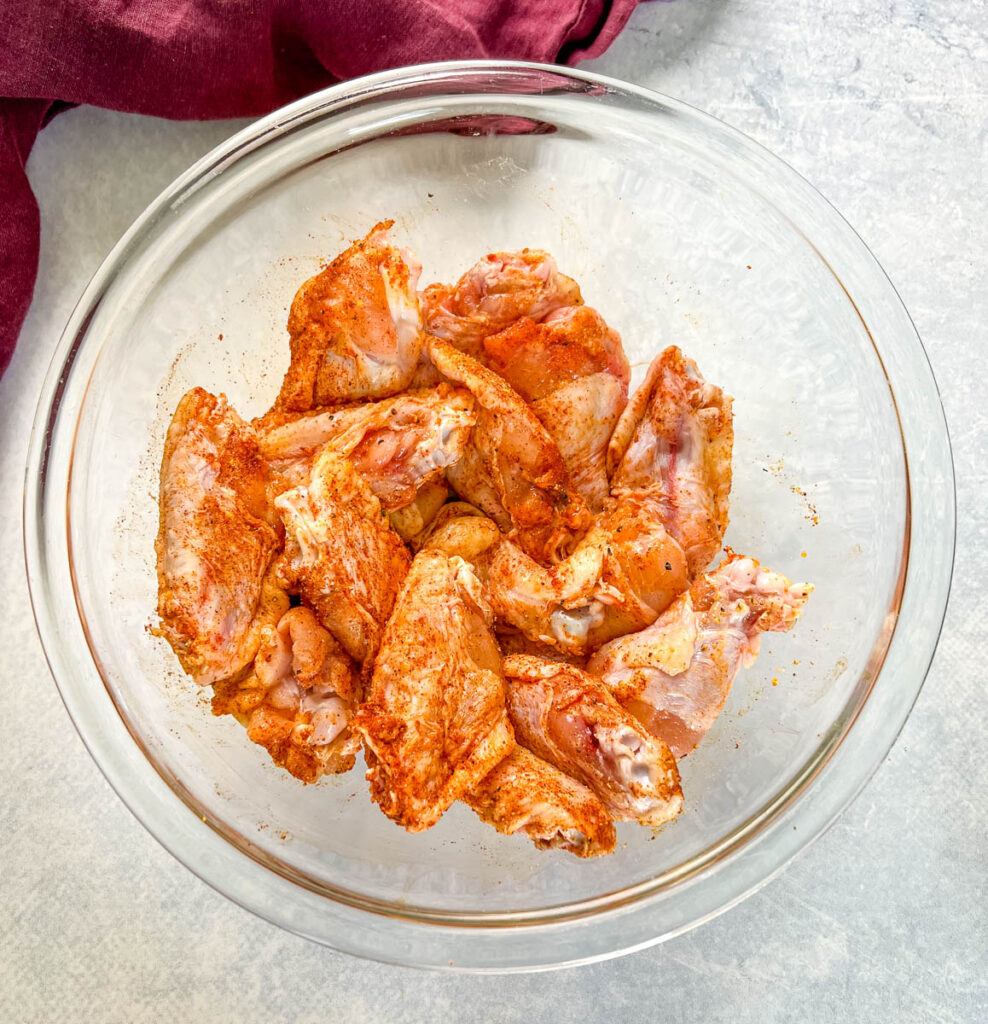 raw hot lemon pepper chicken wings seasoned in a glass bowl