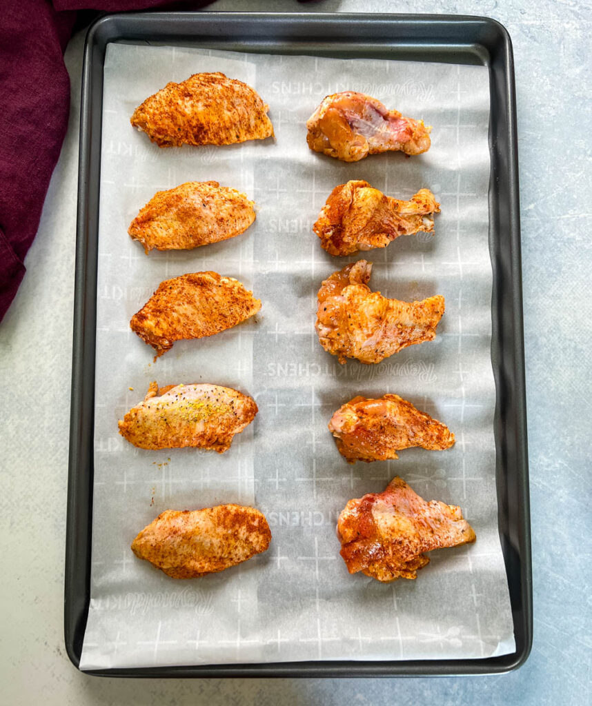 raw hot lemon pepper chicken wings on a sheet pan with parchment paper