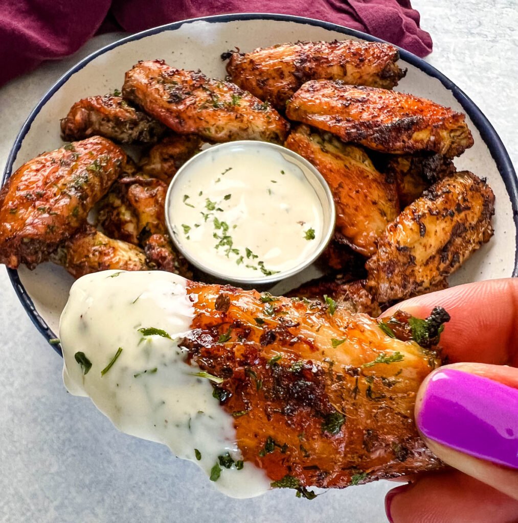person holding naked chicken wing with ranch dressing