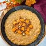 sweet potato oatmeal in a black bowl topped with granola and honey