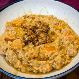 sweet potato oatmeal in a black bowl topped with granola and honey