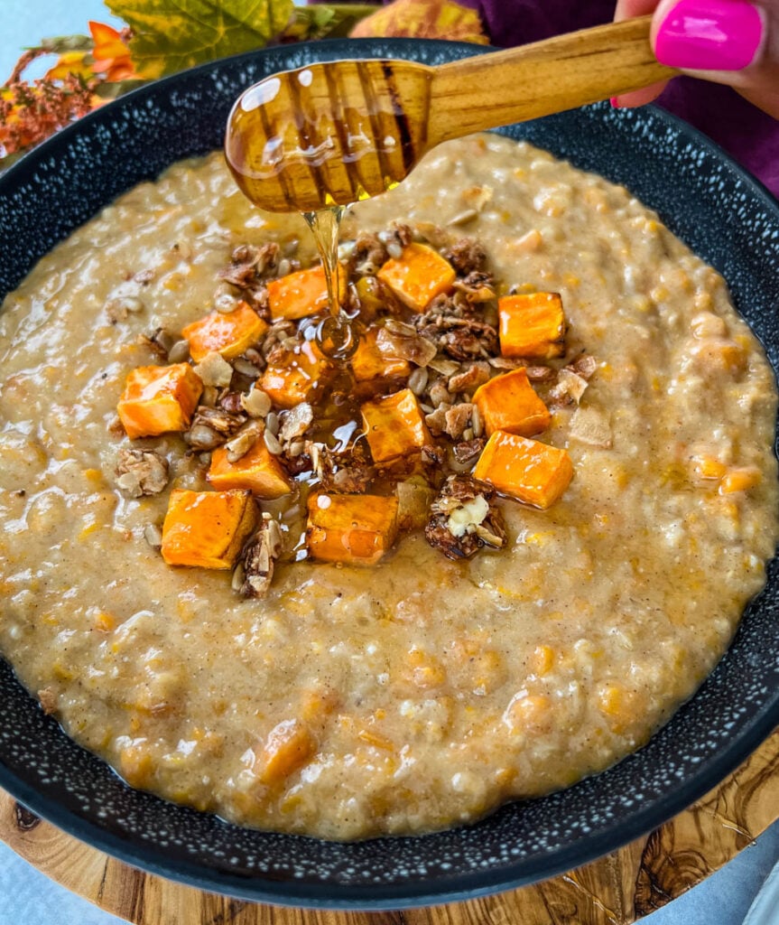 sweet potato oatmeal in a black bowl topped with granola and honey