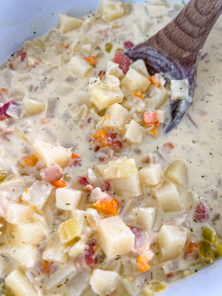 bacon potato soup in a pot with a wooden spoon