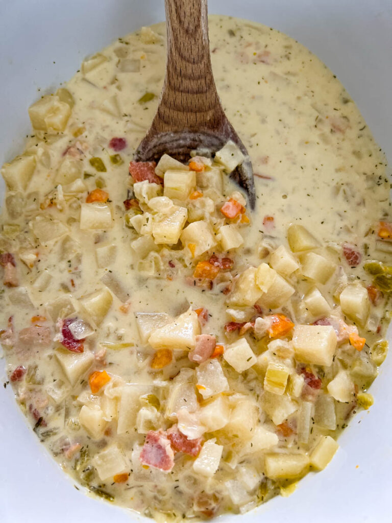 bacon potato soup in a pot with a wooden spoon