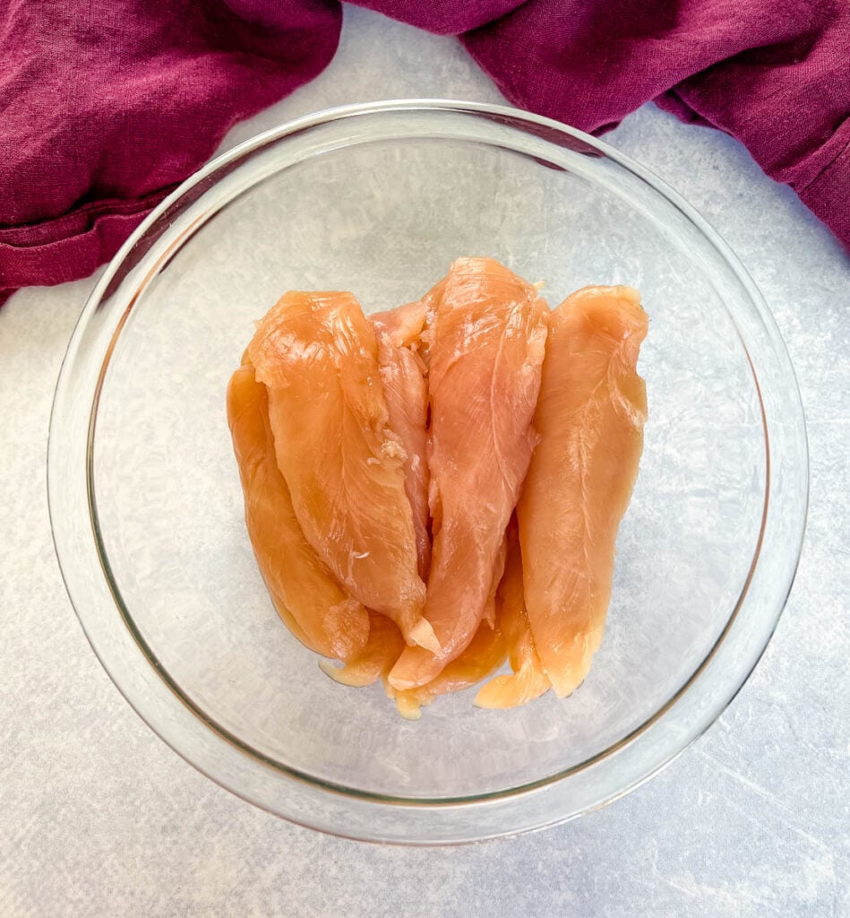 raw chicken tenderloins in a glass bowl