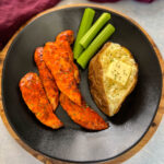 buffalo chicken tenders on a plate with celery, and a baked potato