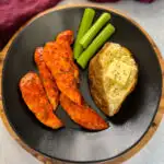 buffalo chicken tenders on a plate with celery, and a baked potato