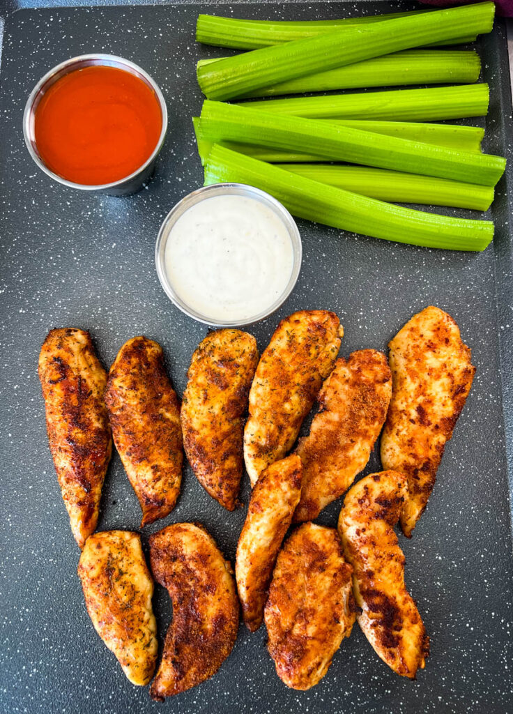 buffalo chicken tenders on a plate with celery, ranch, and buffalo sauce