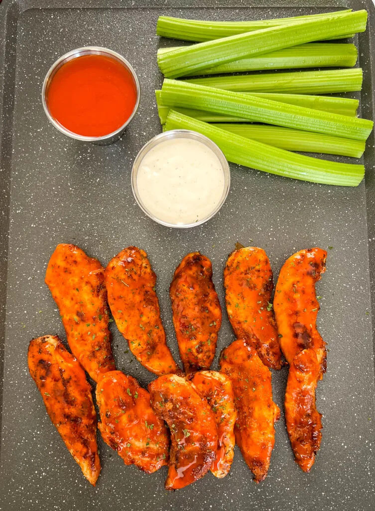 buffalo chicken tenders on a plate with celery, ranch, and buffalo sauce