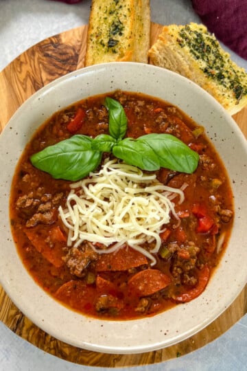 pizza soup with ground beef, pepperoni, mozzarella, and basil in a bowl
