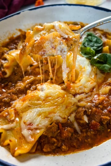 cheese pull of lasagna soup in a bowl