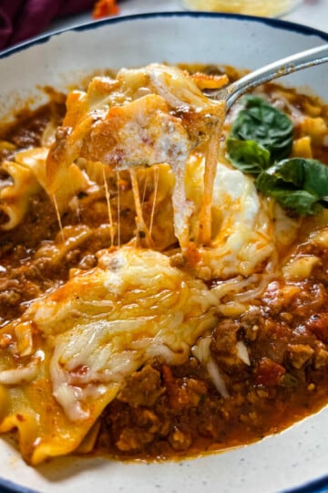 cheese pull of lasagna soup in a bowl