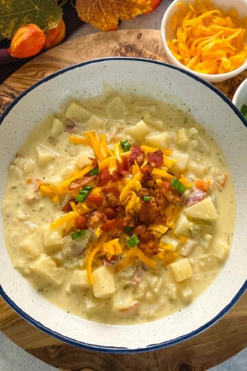slow cooker loaded potato soup in a white bowl with bacon and cheese