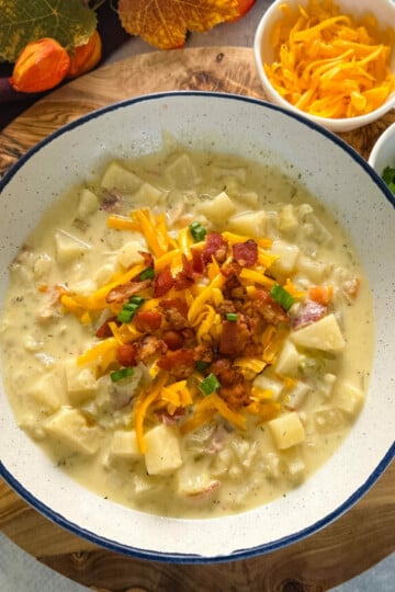 slow cooker loaded potato soup in a white bowl with bacon and cheese