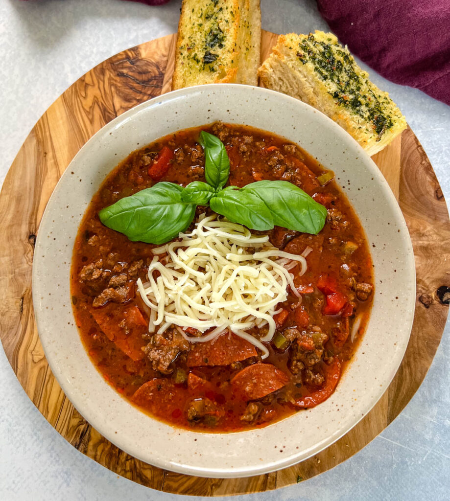 pizza soup with ground beef, pepperoni, mozzarella, and basil in a bowl