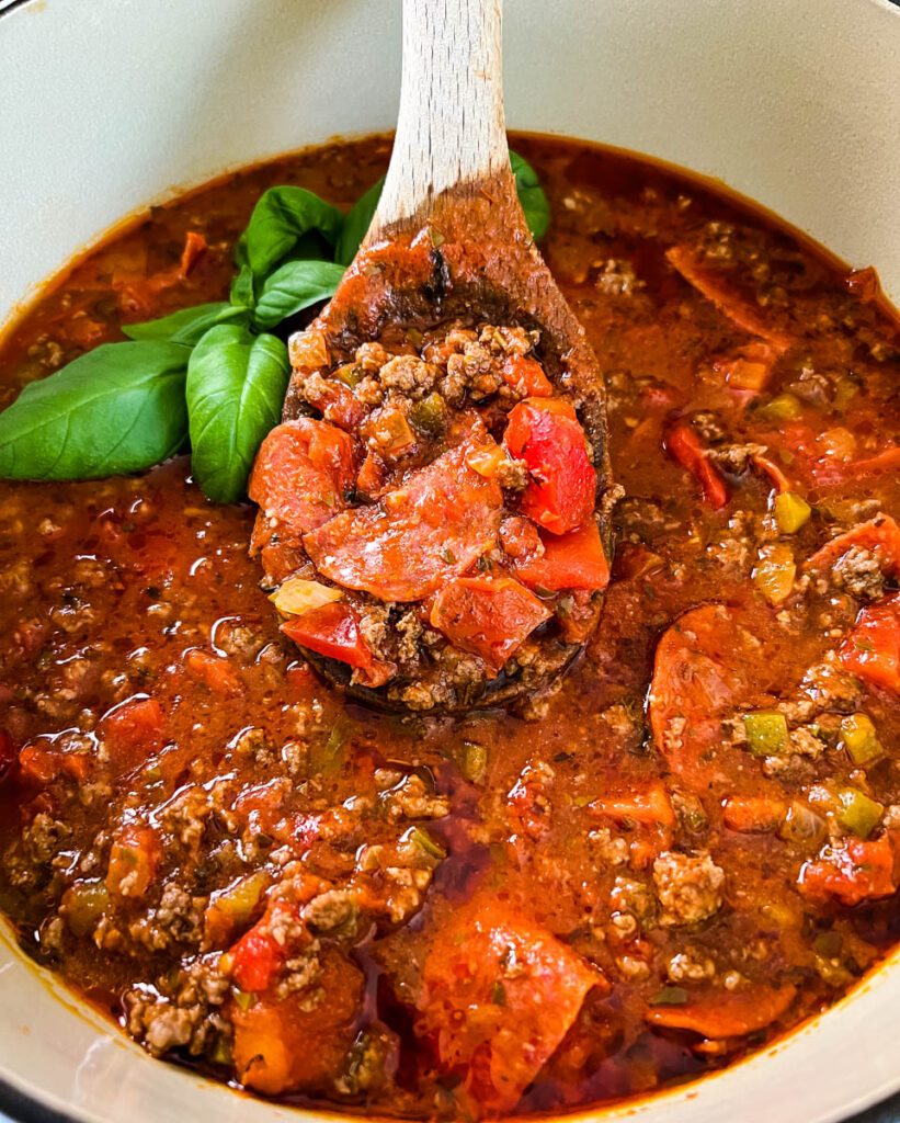 pizza soup with beef, pepperoni, and basil in a pot