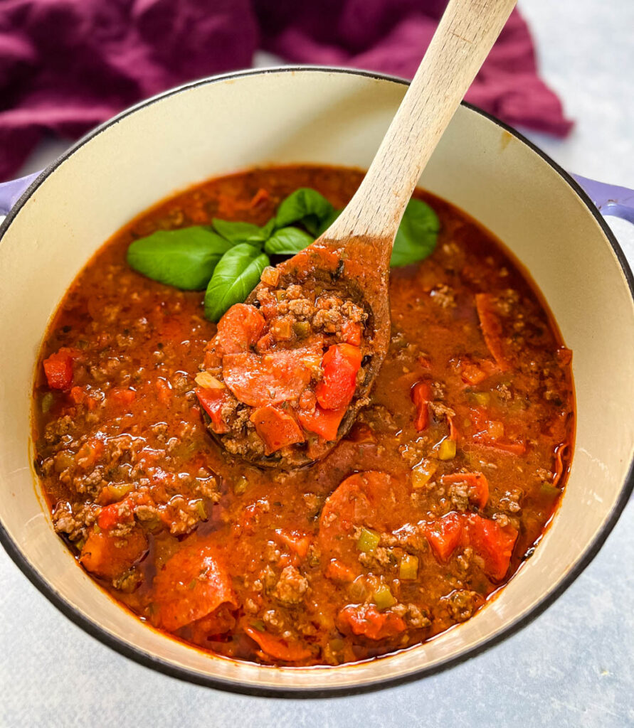 pizza soup with beef, pepperoni, and basil in a pot