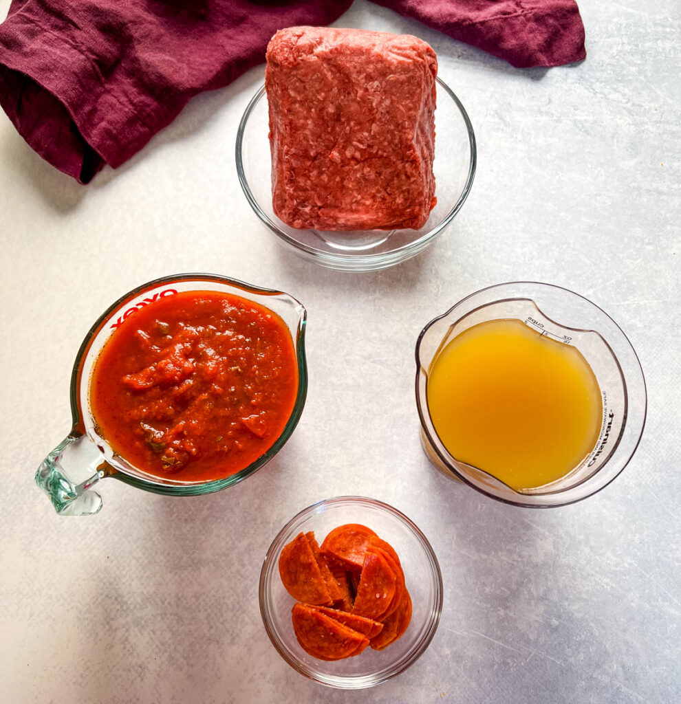 ground beef, marinara sauce, beef broth, and pepperoni in separate glass bowls