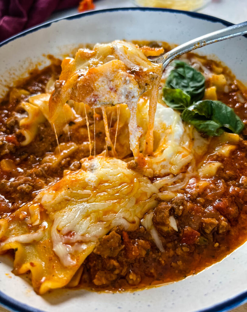 cheese pull of lasagna soup in a bowl