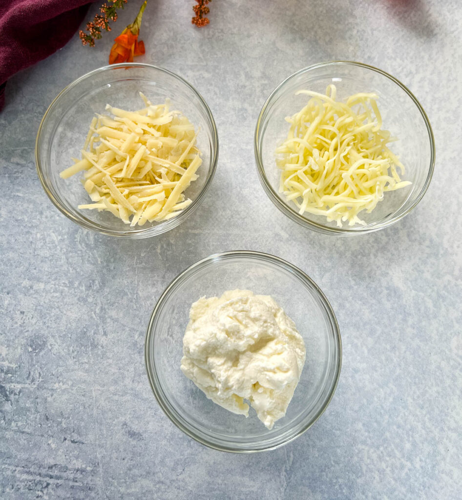 mozzarella, parmesan, and ricotta cheese in separate glass bowls