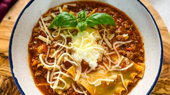 beef lasagna soup with basil and cheese in a bowl