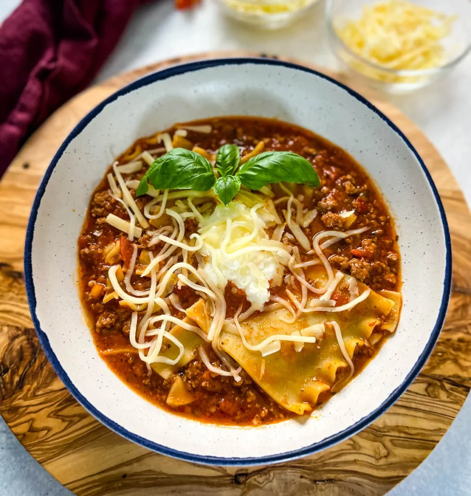 beef lasagna soup with basil and cheese in a bowl