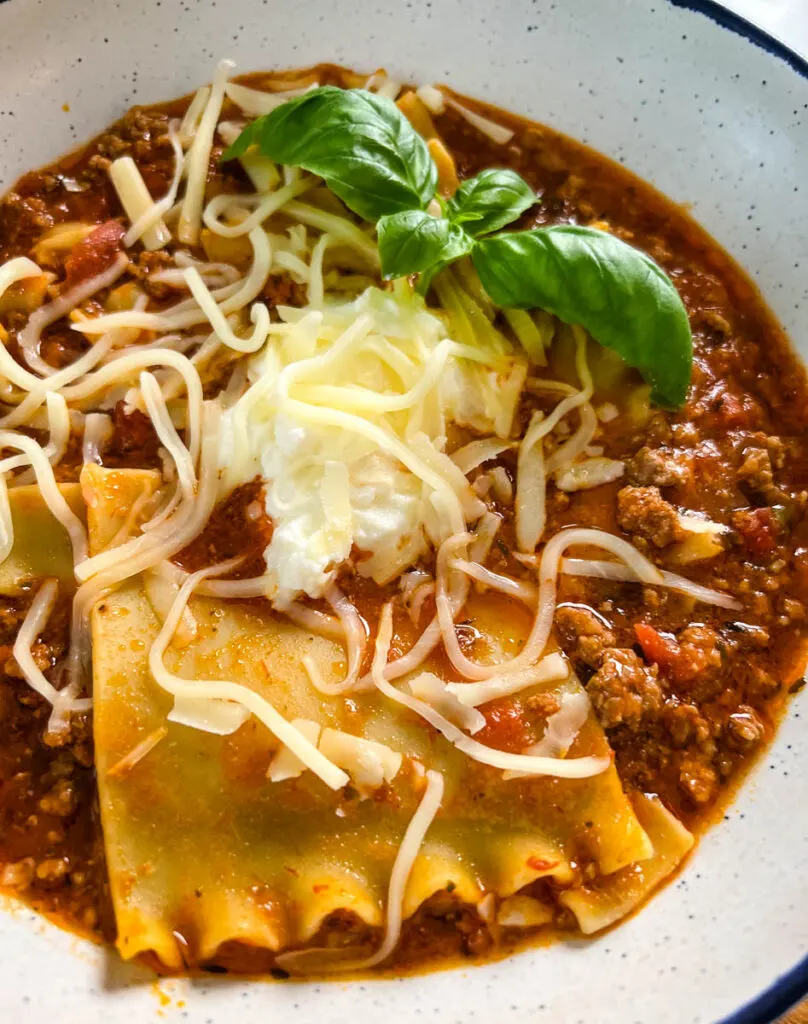 beef lasagna soup with basil and cheese in a bowl