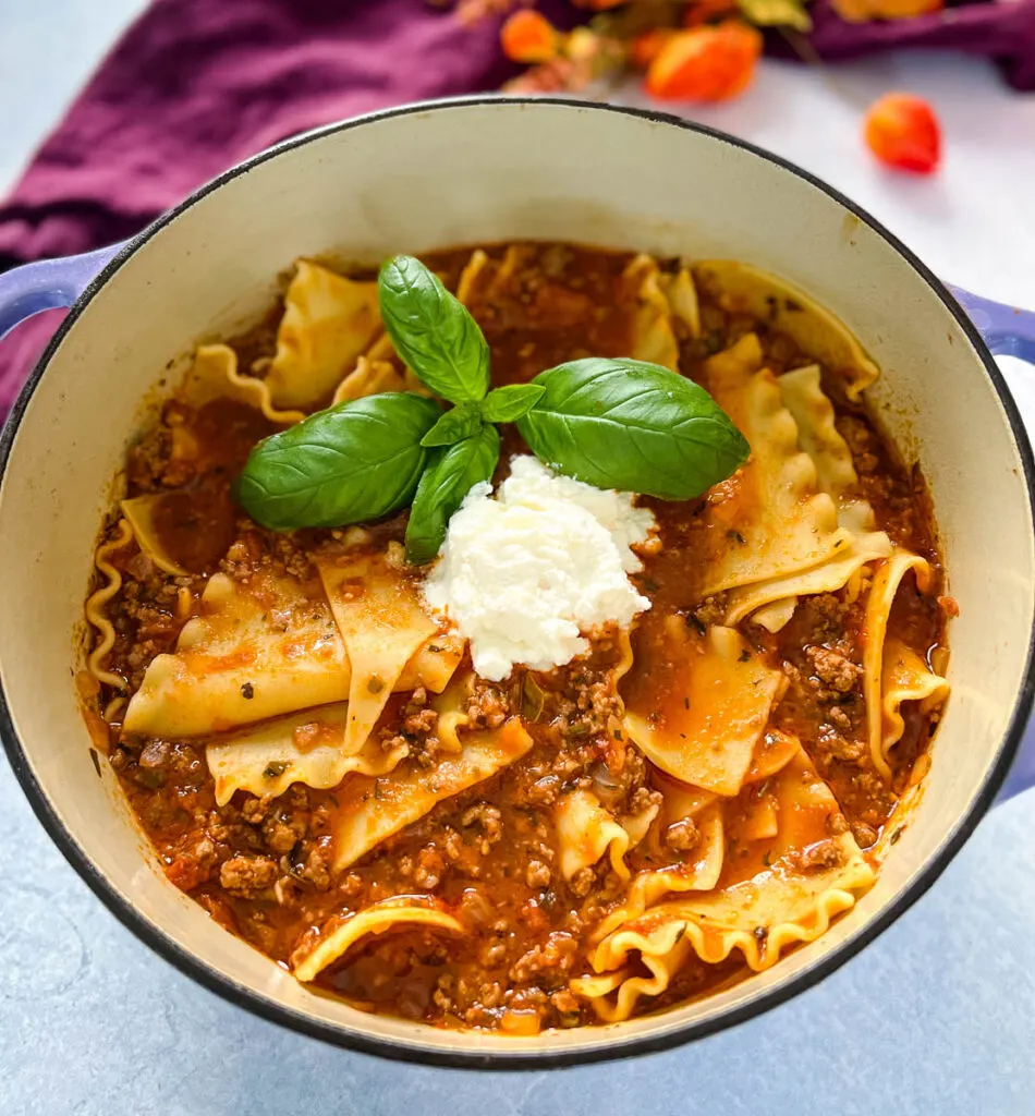 beef lasagna soup with basil and cheese in a pot