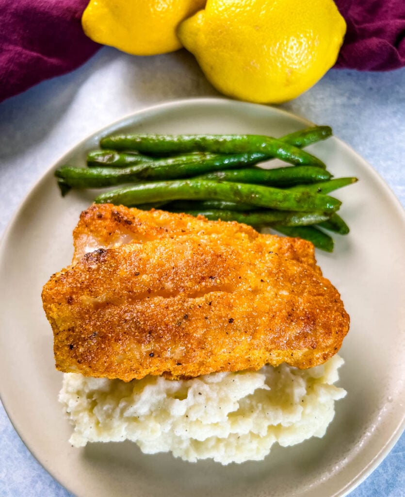 lemon pepper fish, mashed potatoes, and green beans on a plate