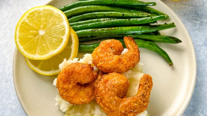 lemon pepper shrimp, mashed potatoes, and green beans on a plate
