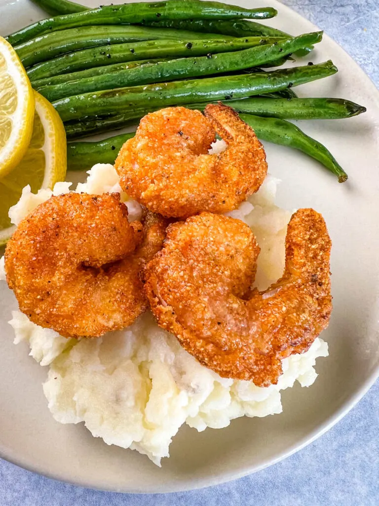 lemon pepper shrimp, mashed potatoes, and green beans on a plate