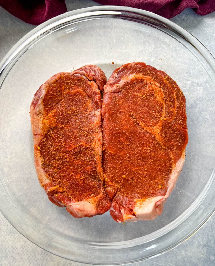 seasoned steaks in a glass pan