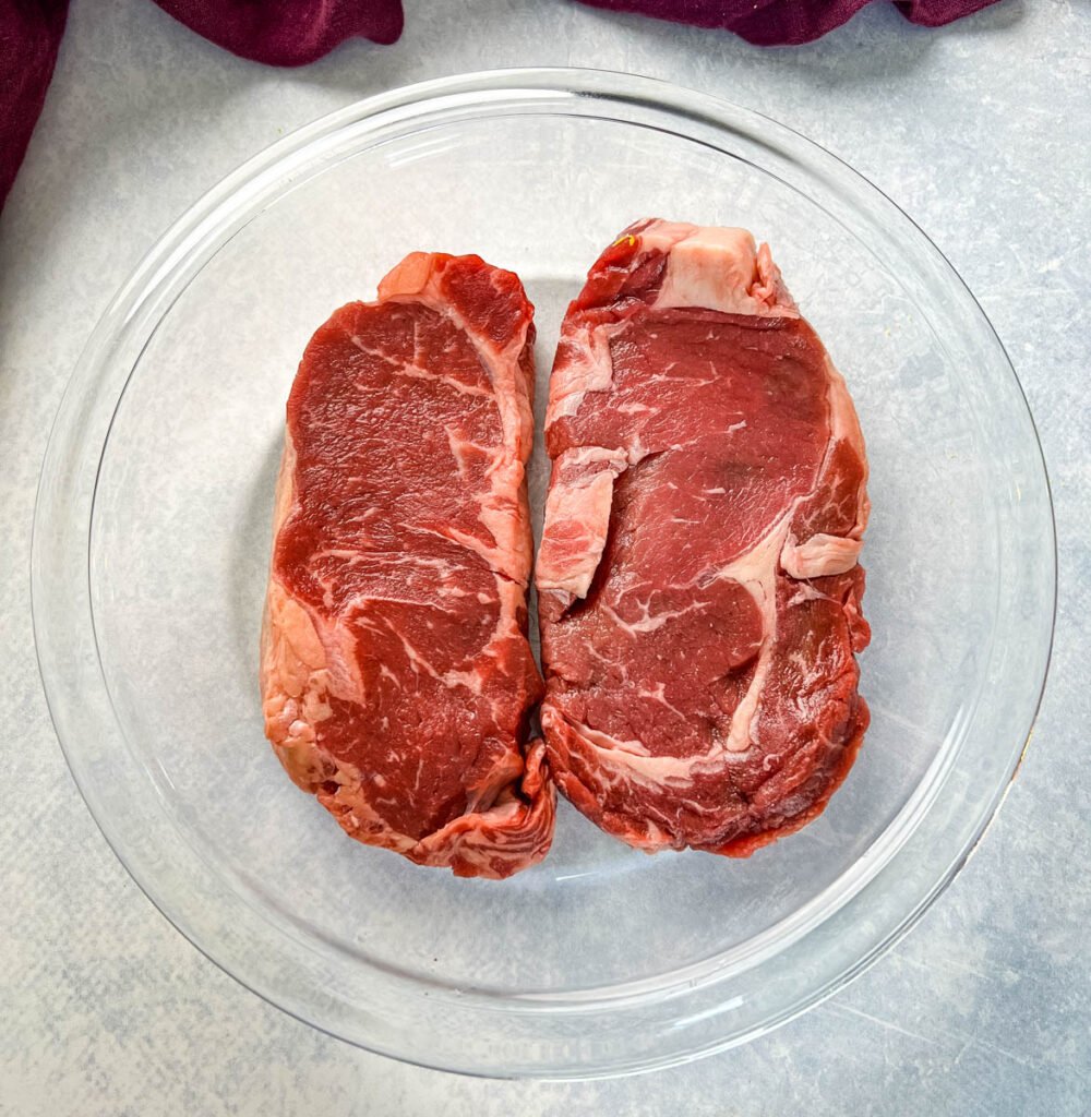 raw steaks in a glass pan