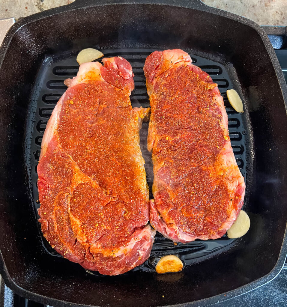 raw steaks in a cast iron skillet