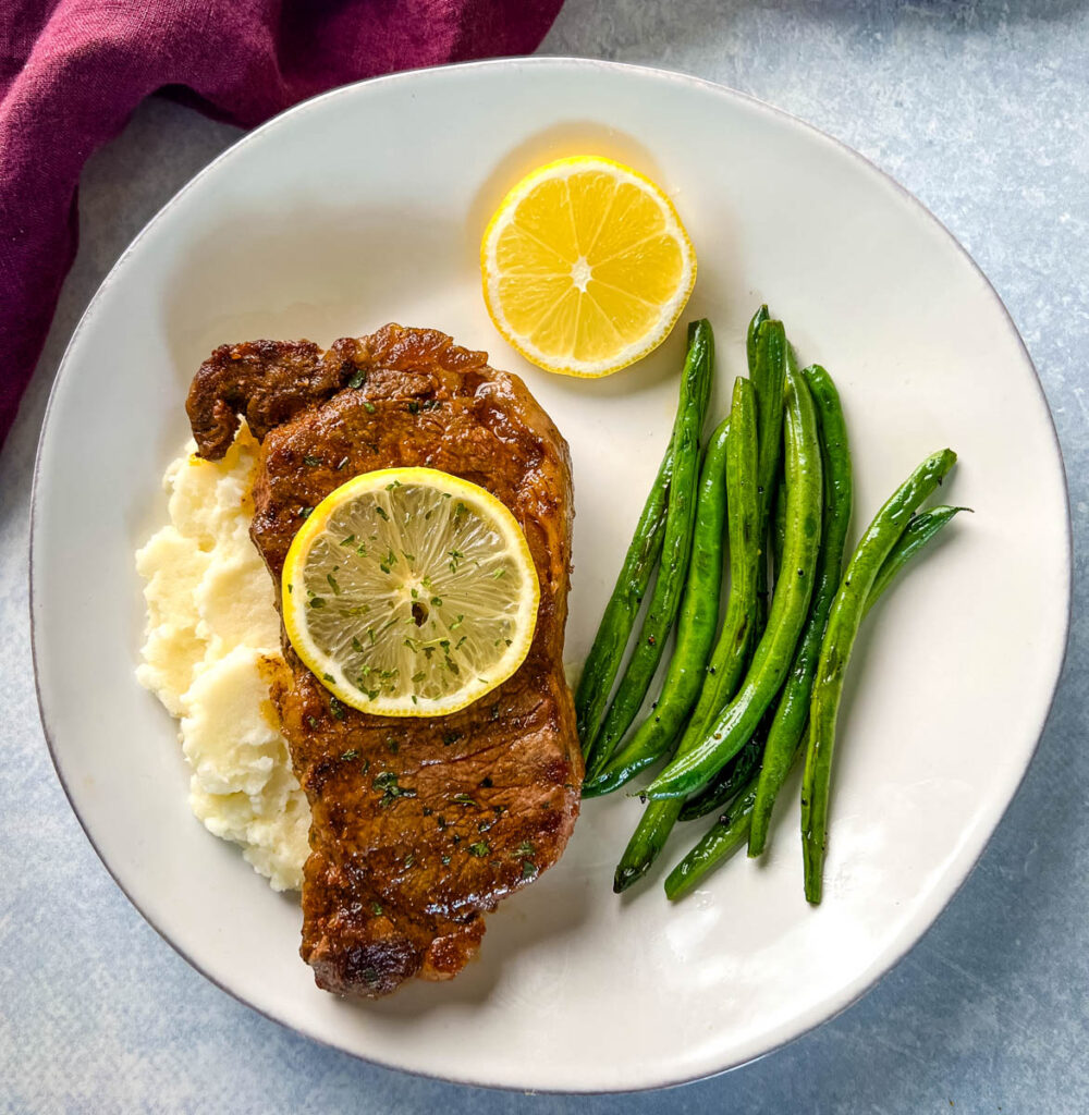 lemon pepper steak with lemon, mashed potatoes, and green beans